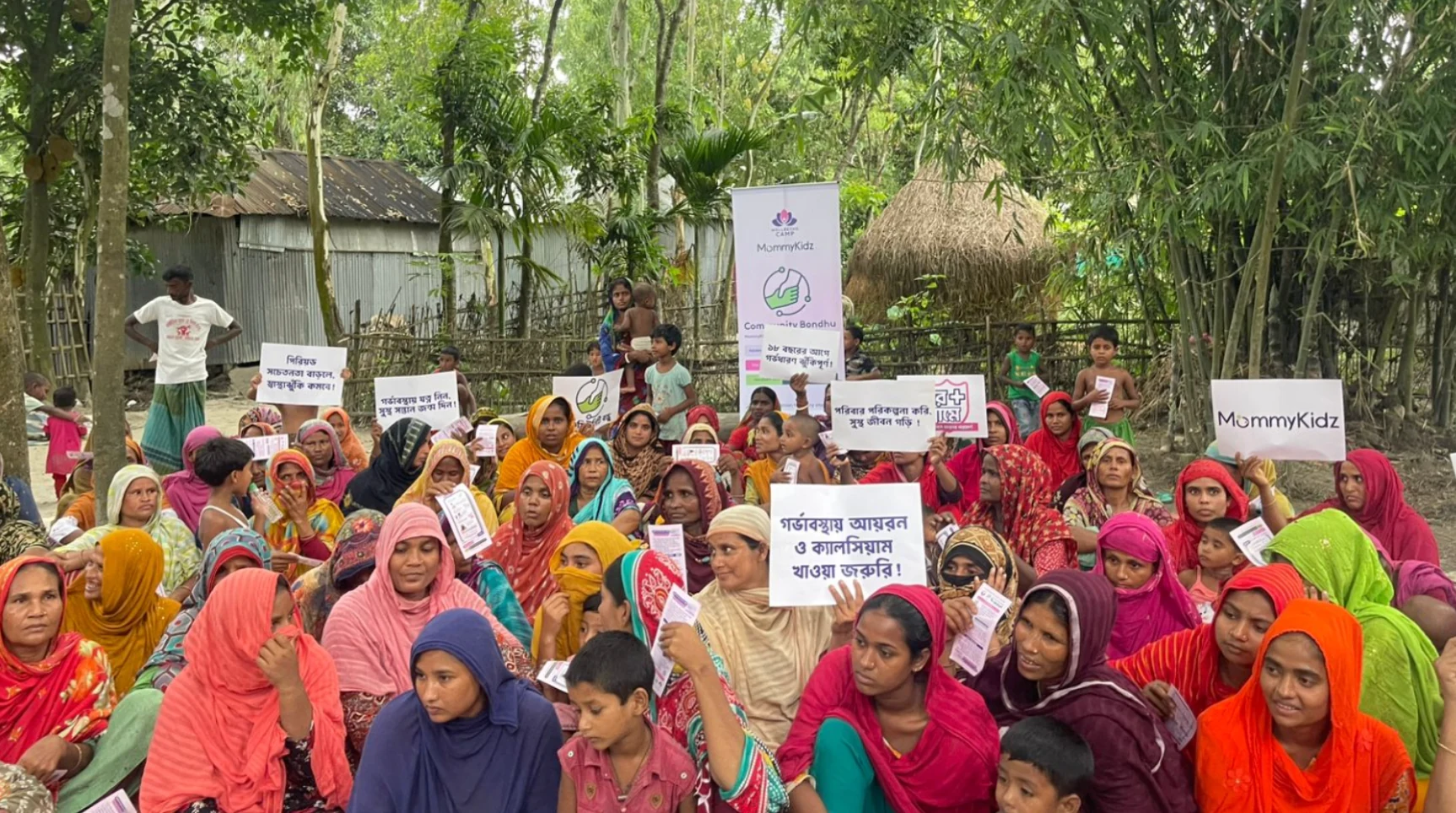 Participants seated outdoors with information materials and awareness placards