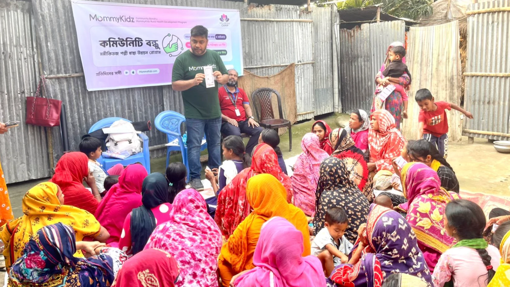 A Community Bondhu facilitator presenting a leaflet to a seated group